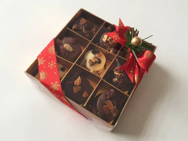 assorted pralines in a box with red ribbon and holiday decoration for christmas gift