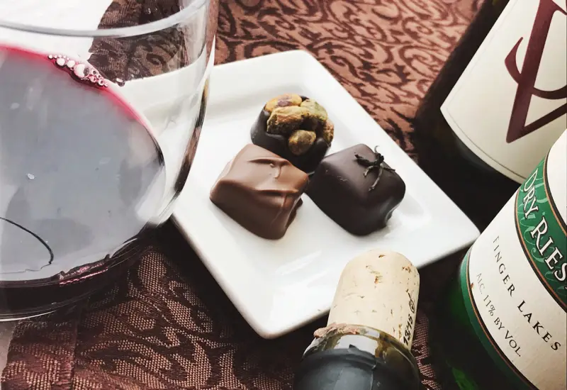 wine glass bottle and chocolates on a patterned cloth